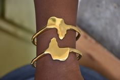 a woman's arm with two gold bracelets on it