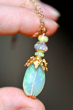 This opal Talisman glistens like a starlight, possessing pinfire specks which sparkle in hues of green and blue. Due to its crystalline composition, the opal features an ever-changing light display a varying ability to be transparent and to glowing intensely. Its magical coloration and markings make it a truly magical stone. The pendant has three faceted opals atop with the smaller 14K gold filled bead toppers. The large opal measures 1” and the large gold bead topper is made of 14k Gold Vermeil Spiritual Opal Necklace In Iridescent Color, Iridescent Opal Spiritual Necklaces, Iridescent Opal Cabochon Jewelry, Iridescent Opal Pendant Jewelry, Fusion Style Opal Gemstone Jewelry, Green Opal Birthstone Jewelry, Unique Iridescent Opal Jewelry, Fusion Style Opal Jewelry Gift, Fusion Style Opal Jewelry For Gifts