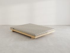 a mattress sitting on top of a wooden frame in an empty room with white walls