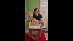 a woman holding up a birthday card in a box