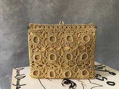 a gold purse sitting on top of a white cake covered in frosting and crochet