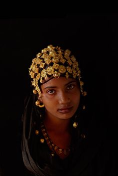 a woman wearing a headdress with gold flowers on it's head and necklace