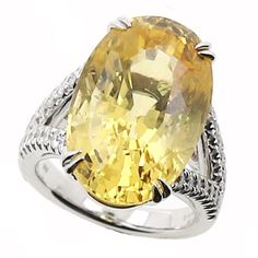 This yellow sapphire and diamond ring has a 19.73 oval shape center yellow sapphire that is GIA certified and a total carat weight of 0.60cts in a split shank semi mounting made of 14 karat white gold. R896-YSA14W Fine Yellow Oval Sapphire Ring, Elegant Yellow Oval Sapphire Ring, Yellow Oval Sapphire Ring With Prong Setting, Yellow Oval Sapphire Diamond Ring, Oval Yellow Sapphire Ring With Diamonds, Luxury Yellow Oval Sapphire Ring, Oval Yellow Sapphire Ring With Center Stone, Oval Yellow Sapphire Ring With Prong Setting, Classic Yellow Sapphire Ring With Accent Stones