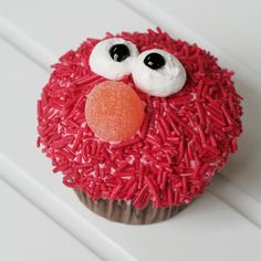 a cupcake decorated with red sprinkles and googly eyes