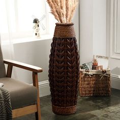 a tall vase sitting on top of a floor next to a chair