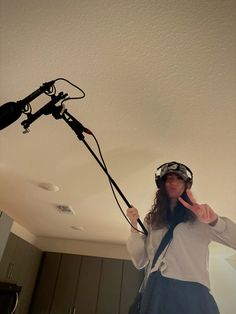 a woman wearing a helmet and holding a camera in her hand while standing under a ceiling light