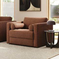 a living room with two brown chairs and a table in front of a large window