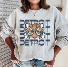 This Detroit Baseball Sweatshirt is the perfect game day apparel. Show your Tigers Baseball pride with this fun retro inspired Detroit crewneck. If you are a Tigers fan then this cozy sweatshirt is a must have to add to your collection. This is a looser fit sweatshirt, but true to size. We recommend sizing up 2 sizes if you want a trendy oversized look. - M A T E R I A L S - Gildan® Sweatshirt 8 oz./yd² (US) 50/50 cotton/polyester Heather Sport colors: 60/40 polyester/cotton Loose Fit Ribbed Knit Collar to retain shape - C A R E  I N S T R U C T I O N S - Inside out, wash with delicate cycle Do not iron directly onto the design Do not bleach Do not dry clean. - M A T E R I A L S - Gildan® Sweatshirt 8 oz./yd² (US) 50/50 cotton/polyester Heather Sport colors: 60/40 polyester/cotton Loose Fi Baseball Opening Day, Detroit Sports, Baseball Sweatshirts, Vintage Detroit, Tigers Baseball, Crewneck Vintage, Game Day Outfit, Perfect Game, Gildan Sweatshirts