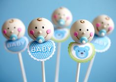 baby shower cake pops with blue and green decorations on them, sitting in front of a blue background