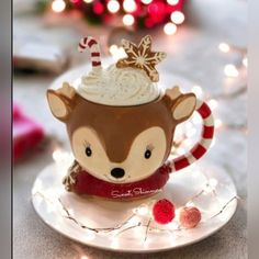 a small cup filled with whipped cream and topped with a reindeer's head sitting on top of a saucer