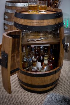 a wooden barrel filled with bottles and glasses on top of a carpeted floor next to barrels