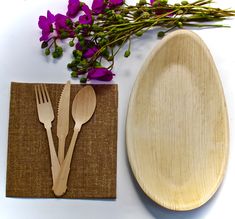 wooden utensils and spoons are sitting next to a paper plate with purple flowers on it