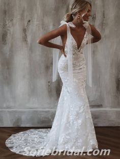 a woman in a white wedding dress standing on a wooden floor with her back to the camera