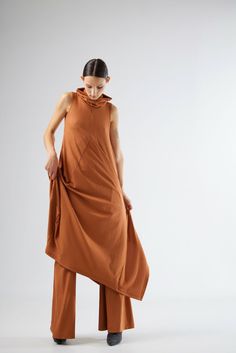 This dress,crafted from high-quality knit fabric,offers a fluid and graceful silhouette that flatters all body types.The sleeveless design is ideal for layering,allowing you to transition effortlessly from season to season.The standout feature of this dress is its unique cowl neckline,adding a touch of contemporary flair to a classic piece.The asymmetrical hemline creates a dynamic visual effect,ensuring you stand out in any crowd.The diagonal seam lines not only enhance the dress's aesthetic appeal but also contribute to its structured fit.Ideal for casual outings or semi-formal events,this terracotta midi dress is versatile enough to be dressed up or down.Pair it with sandals for a relaxed daytime look or with heels and statement jewelry for an evening ensemble. Sleeveless Long Dress, Dress Aesthetic, Dress Crafts, Cowl Neckline, Front Row, Statement Jewelry, Cloth Bags, Semi Formal, Formal Event