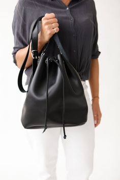 Of great quality, this leather women's handbag is a season's statement piece. It is handmade with care to the detail and to last for years. Its modern, minimal design will never go out of fashion.  The wide variety of colors we offer, make this shoulder bucket bag match any day or night look. Its unstructured shape provides  plenty of  room for your personal items.  The metallic backles offer durability, while its drawstring secures your stuff. The strap is long and adjustable.  Made of premium genuine leather, all our bags are handcrafted in Greece. WOULD MAKE A UNIQUE GIFT  2 SIZES  4 LEATHER COLOURS: NATURAL / BLACK/ NUBUCK BROWN / GOLD Womens Bag Bucket shape Adjustable Shoulder Strap Drawstring at the top Durable, Metalic Buckles Without lining Premium Full Grain Leather Handmade in G Cheap Bucket Bag With Chain Strap, Leather Hobo Pouch Bag As Gift, Minimalist Leather Pouch Bag, Soft Leather Clutch Bucket Bag, Modern Leather Pouch Shoulder Bag, Versatile Leather Satchel With Dust Bag, Handmade Leather Hobo Bag In Pouch Shape, Elegant Black Bucket Bag For Gift, Black Satchel With Dust Bag As Gift