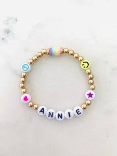 🌈 Colorful emoji beads with matte gold accents make this name bracelet one of the cutest. Can be made in adult or child sizes. Please note name/word and any color preference of the heart, star or peace sign in the personalization section. 🌈 Listing is for ONE bracelet.  🌈 Sizing length is as follows:  Women's small: 6.5 inches Women's medium: 7 inches Women's large: 7.5 inches Women's XL: 8 inches Children's 4-5 years old: 5.75 inches Children's 6-7 years old: 6 inches Children's 8-9 years old: 6.25 inches Children's 10-13 years old: 6-7 inches **Please measure wrist before ordering. Bracelets are stretchy but you do not want them to be super loose around your wrist.  🌈 All orders are FINAL SALE. These are custom bracelets made to order. PLEASE DOUBLE CHECK ALL SPELLING AND COLOR SELEC Fun Personalized Everyday Jewelry, Personalized Fun Everyday Jewelry, Playful Gold Beaded Bracelets For Everyday, Playful Gold Friendship Bracelets With Letter Beads, Cute Name Bracelet With Round Beads For Everyday, Cute Everyday Name Bracelet With Round Beads, Cute Gold Charm Bracelet With Letter Beads, Cute Personalized Gold Stretch Bracelet, Playful Letter Beads Name Bracelet For Friendship