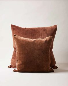 two brown pillows sitting next to each other