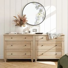 a wooden dresser with a round mirror above it