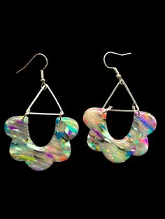 a pair of earrings with white and multicolored material hanging from metal hoops