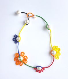 a multicolored beaded necklace with flowers and pearls on a white table top