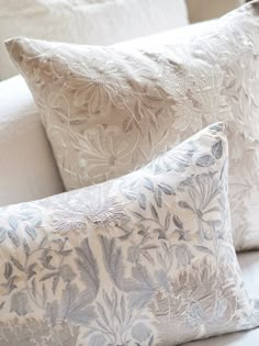 the pillows are all lined up on the bed together, and one is white with blue flowers