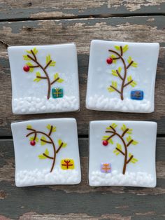 four white plates with designs on them sitting on a wooden surface