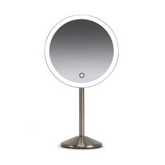 a round mirror sitting on top of a metal stand