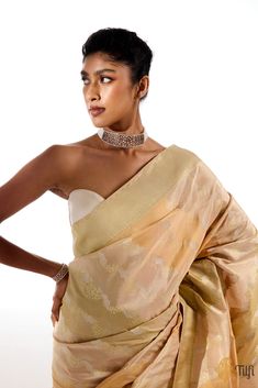 "\u00a0\nGabrielle\nAn exquisite Banarasi Rangkat saree handwoven in a distinctive combination of soft Katan silk and glistening gold Tissue silk. Adorned with an undulating aadha jangla pattern in roopa sona zari, the drape\u00a0features\u00a0motifs inspired by the structures of laces,\u00a0curving forms, and shell shapes\u00a0characteristic\u00a0of Rococo\u00a0fashion, art, and architecture. A magnificent amalgamation of two heritage artistries in a metallic and pastel palette.\u00a0\n\n\nColo Rangkat Saree, India Inspired, Peach And Green, Pastel Palette, Katan Silk, Weaving Process, Silver Screen, Handloom Saree, Rococo