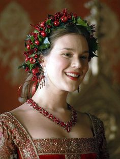 a woman in a red and gold dress with a flower crown on her head smiling