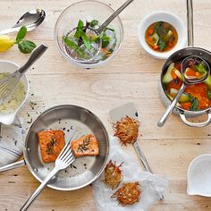 a table topped with bowls and pans filled with different types of food next to utensils