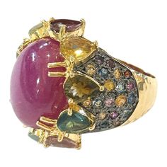 This is part of Chairish’s Fine Jewelry assortment.  Center Oval Shape Natural Ruby - 4 Carat  Multi color Natural Sapphires from Sri Lanka 2.50 Carat  Round and Pear shape Brilliant Colors: Pink, Yellow, Rose, Green and Blue   This Ring is from the "Orient" traveling collection are the epitome of elegance and versatility. It offers a perfect blend of day to night and swimwear to evening wear, allowing you to effortlessly transition between different occasions and outfits.  Wearing these spectac Luxury Multicolor Oval Gemstones, Fine Jewelry Multicolor Cabochon Gemstones, Multicolor Cabochon Gemstones Fine Jewelry, Multicolor Cabochon Gemstones For Fine Jewelry, Multicolor Cabochon Rings In Fine Jewelry Style, Luxury Multicolor Cabochon Rings, Multicolor Cabochon Rings Fine Jewelry, Luxury Multi-stone Ruby Ring, Luxury Ruby Ring With Diamond Accents