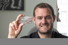 a man holding up a plastic business card