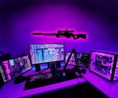 three computer monitors sitting on top of a desk in front of a purple wall with neon lights