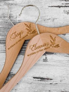 two personalized wooden hangers with leaves on them, one for the bride and one for the groom