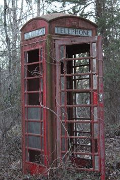 an old red telephone booth in the woods