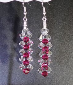 a pair of red and clear crystal earrings hanging from a hook - on earwire