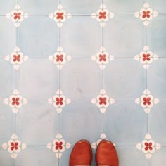 a pair of brown shoes sitting on top of a blue and white tile floor next to a wall