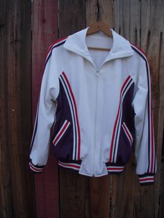 Sturdy terry lined track jacket with fantastic hand applique detail.  Classic track jacket style with full zip closure. Excellent vintage condition. Fully lined in stretch terry.  No size or fabric content tag.  Most likely poly or poly blend. Rib knit cuffs and hem.  All applique hand made and machine attached. Has been successfully machine washed.  Fits like a men's small. Laying flat measures: 23" armpit to armpit 15" bottom edge (hip) 25" neck edge near collar to hem Fitted Sporty Fleece Jacket For Fall, Sporty Fleece-lined Track Jacket For Fall, Sporty Track Jacket With Fleece Lining For Fall, Sporty Cotton Track Jacket For Fall, Fall Sportswear Track Jacket With Fleece Lining, Fall Sports Sweatshirt With Contrast Stripes, Fitted Sportswear Track Jacket With Ribbed Cuffs, Cotton Outerwear With Three Stripes For Fall, Three Stripes Cotton Track Jacket For Winter