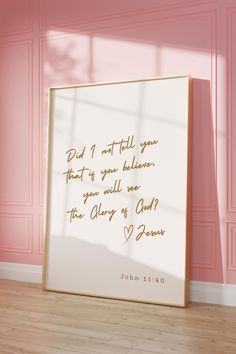 a pink room with a framed quote on the wall next to it and a wooden floor