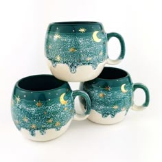 three coffee mugs sitting next to each other with stars and moon designs on them