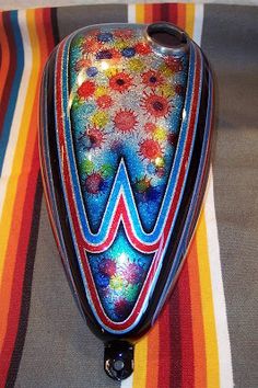 a colorful vase sitting on top of a striped table cloth next to a black object