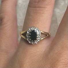 a woman's hand with a ring on it that has a black stone in the middle