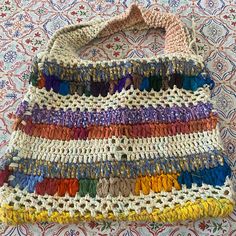 a multicolored crocheted bag sitting on top of a tablecloth covered floor