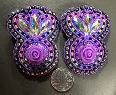 two pieces of purple beaded and crystaled broochies next to a dime