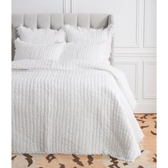 the bed is made with white linens and pillows on top of it, along with an animal print area rug