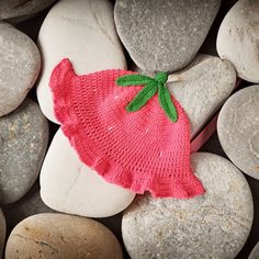 a knitted strawberry hat laying on some rocks