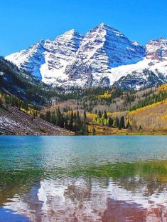 the mountains are covered in snow and fall colors as they reflect on the still water