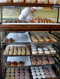 a man standing behind a display case filled with lots of doughnuts and pastries