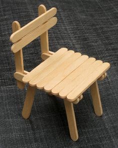 a small wooden chair sitting on top of a gray carpeted floor in front of a black background