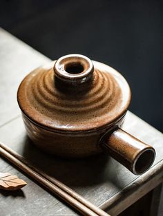 a ceramic pot sitting on top of a wooden table next to a pair of chopsticks